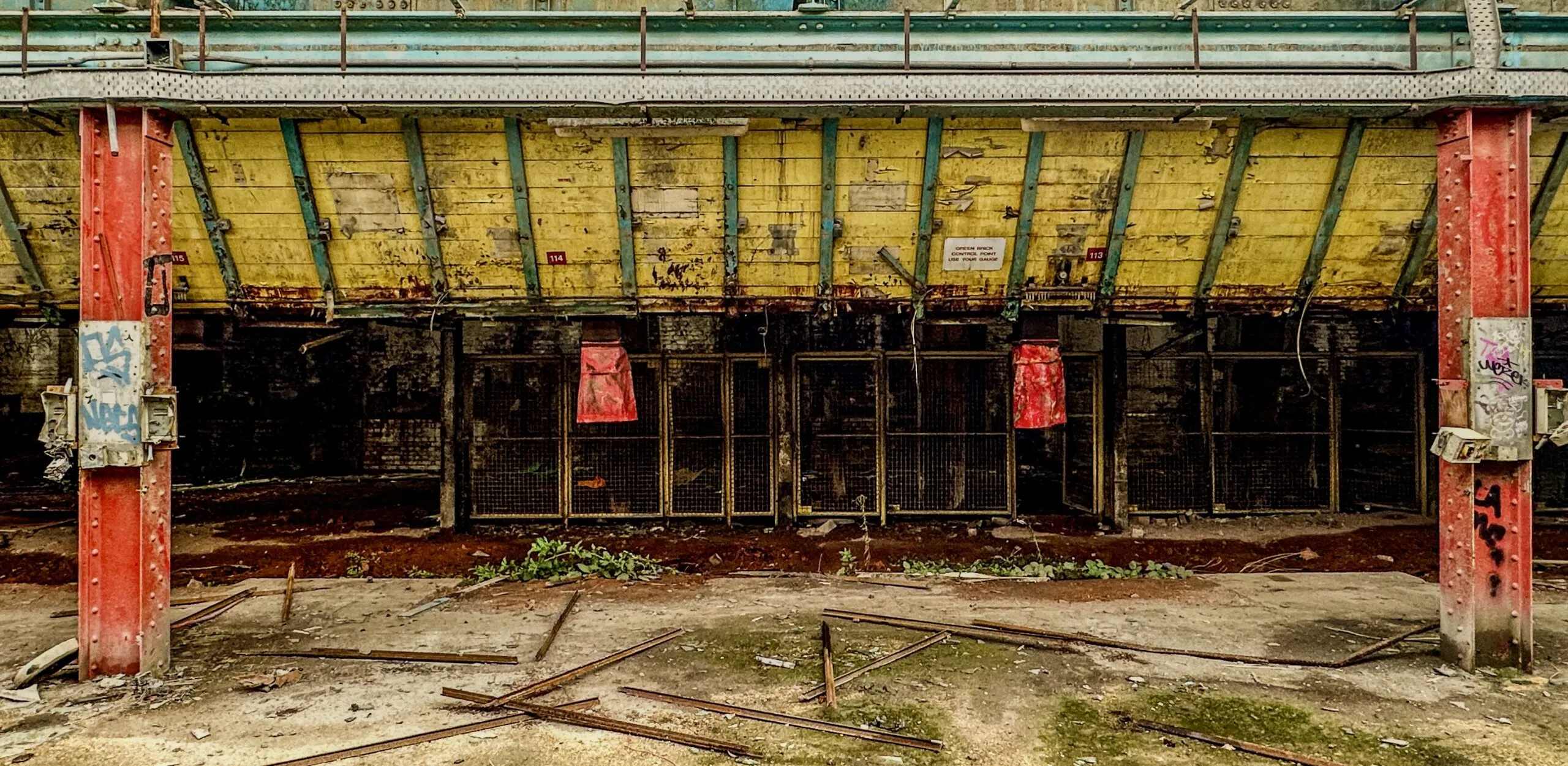 The yellow-painted underside of a kiln gallery carried on red riveted columns, numbered loading bays below